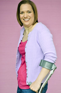 Dawn Grabowski headshot. Dawn is wearing a pink shirt with a lilac sweater. She is using forearm crutches.