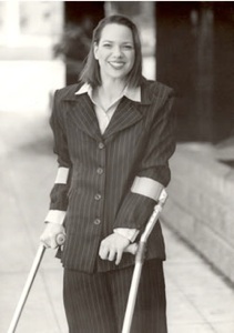 Dawn Grabowski medium headshot, smiling at the camera. She is wearing forearm crutches over a dark suit.