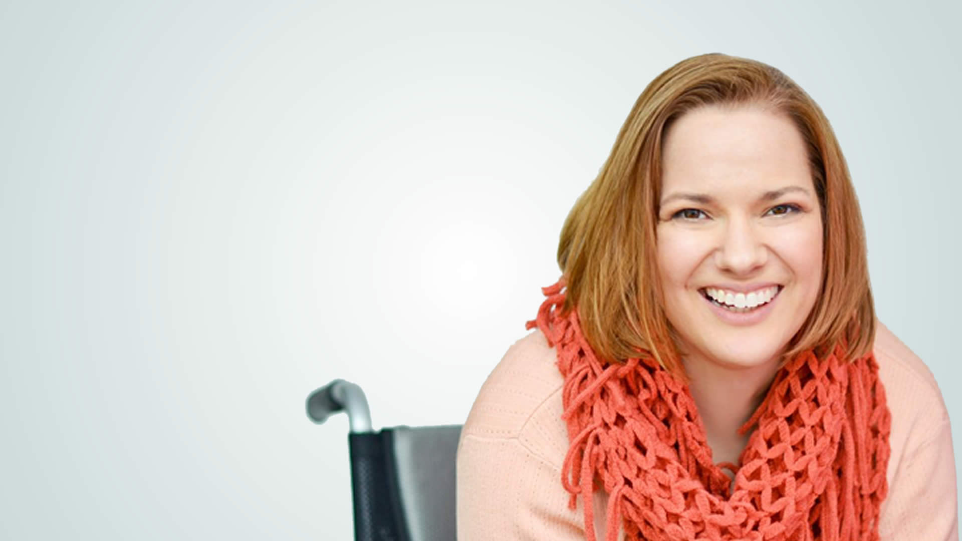 image of Dawn Grabowski sitting in a wheelchair wearing a peachy scarf and pink sweater.