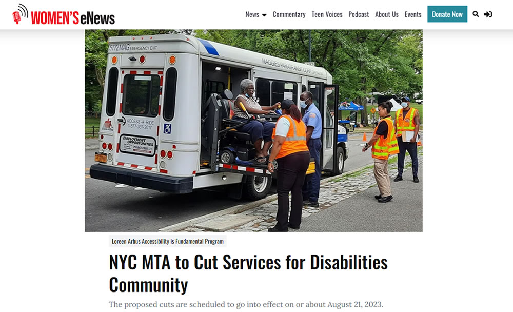Small white bus with wheelchair access parked along a street as bus driver helps load passenger in wheelchair.